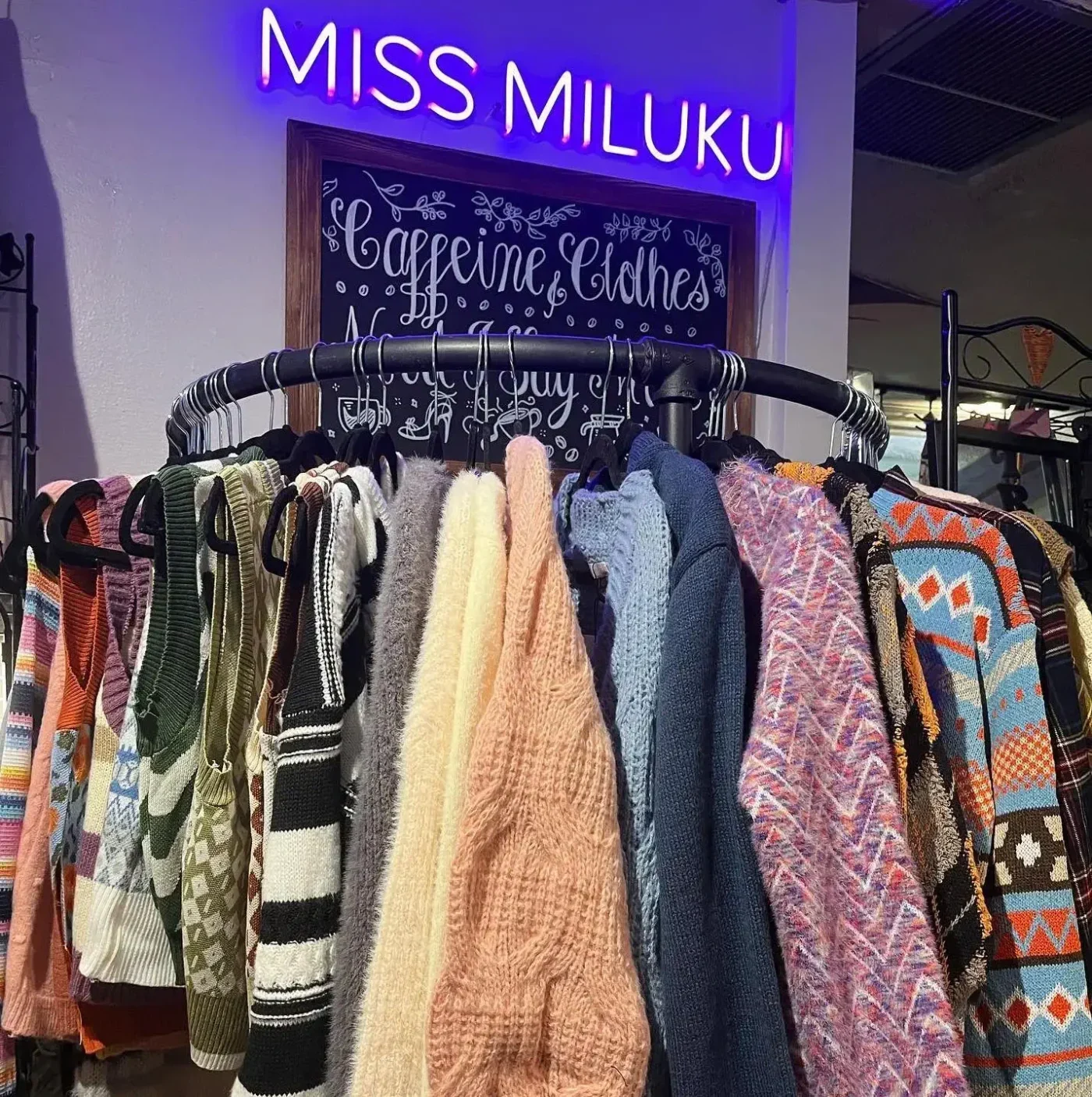 Photo of clothes rack with a neon sign that reads Miss Miluku